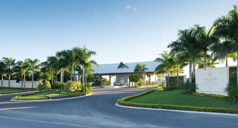 A modern hotel entrance with a covered driveway, palm trees, and a sign reading "Interstate Resort & Spa".