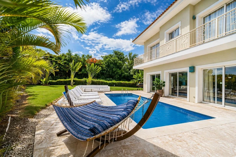 A modern house with a swimming pool, a hammock, and a well-maintained garden.