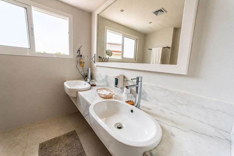 A bathroom with two sinks, a large mirror, and a bathtub.
