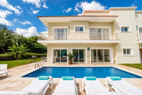 A two-story house with a swimming pool, outdoor seating, and a garden.