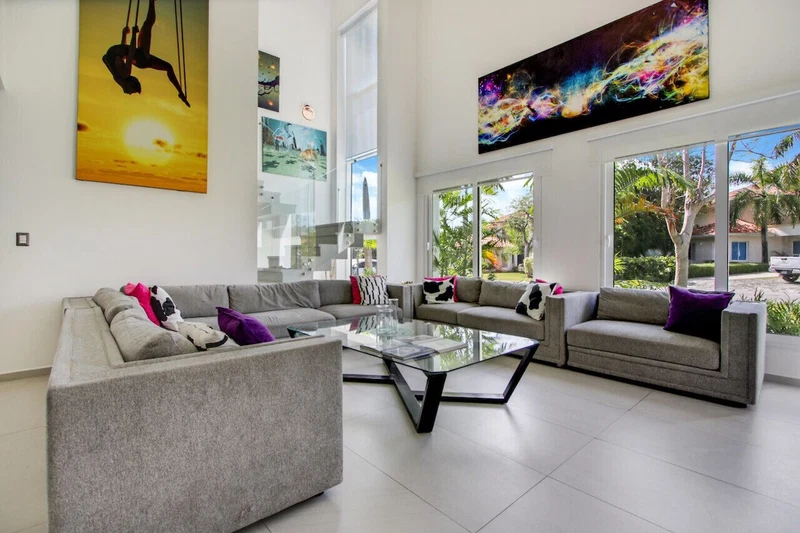 A modern living room with two sofas, a glass coffee table, and large windows offering a view of the outdoors.