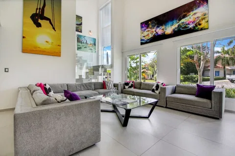 A modern living room with two sofas, a glass coffee table, and large windows offering a view of the outdoors.