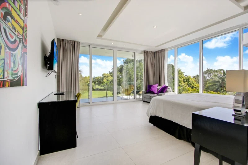 A modern hotel room with a large bed, a desk, and a TV.