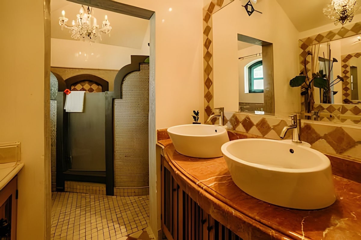 A modern bathroom with two large sinks, a mirror, and a chandelier.