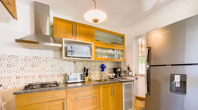 A modern kitchen with wooden cabinets, a stainless steel refrigerator, a microwave, and a gas stove.