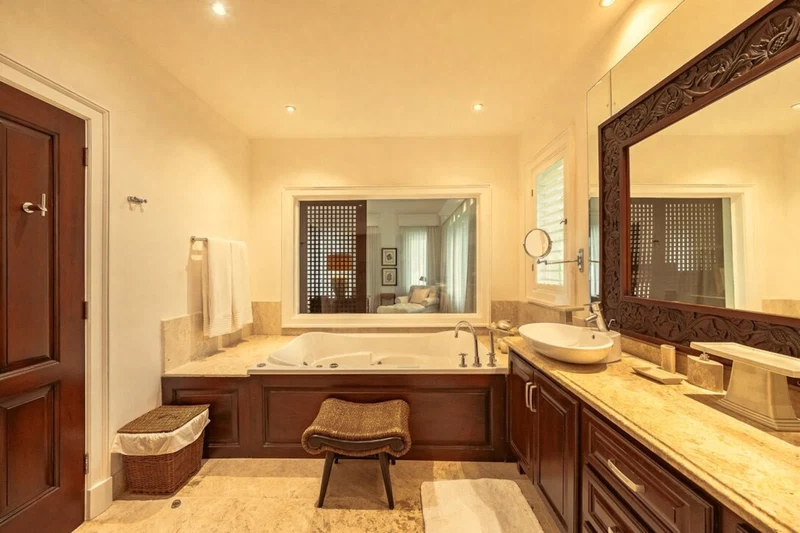 A spacious bathroom with a large bathtub, a vanity with a sink, and a large mirror.
