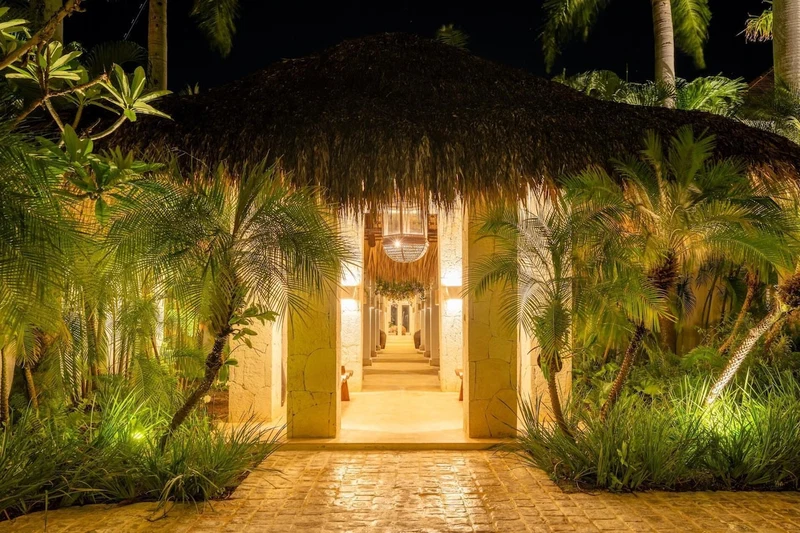 A pathway leading to a thatched-roof structure surrounded by lush greenery.