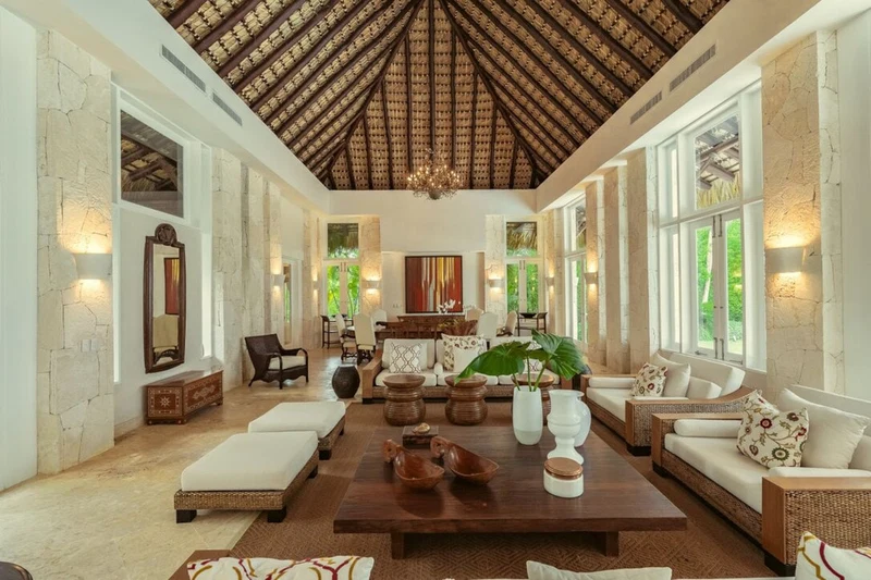 A spacious living room with a high ceiling, large windows, and a central coffee table with decorative items.